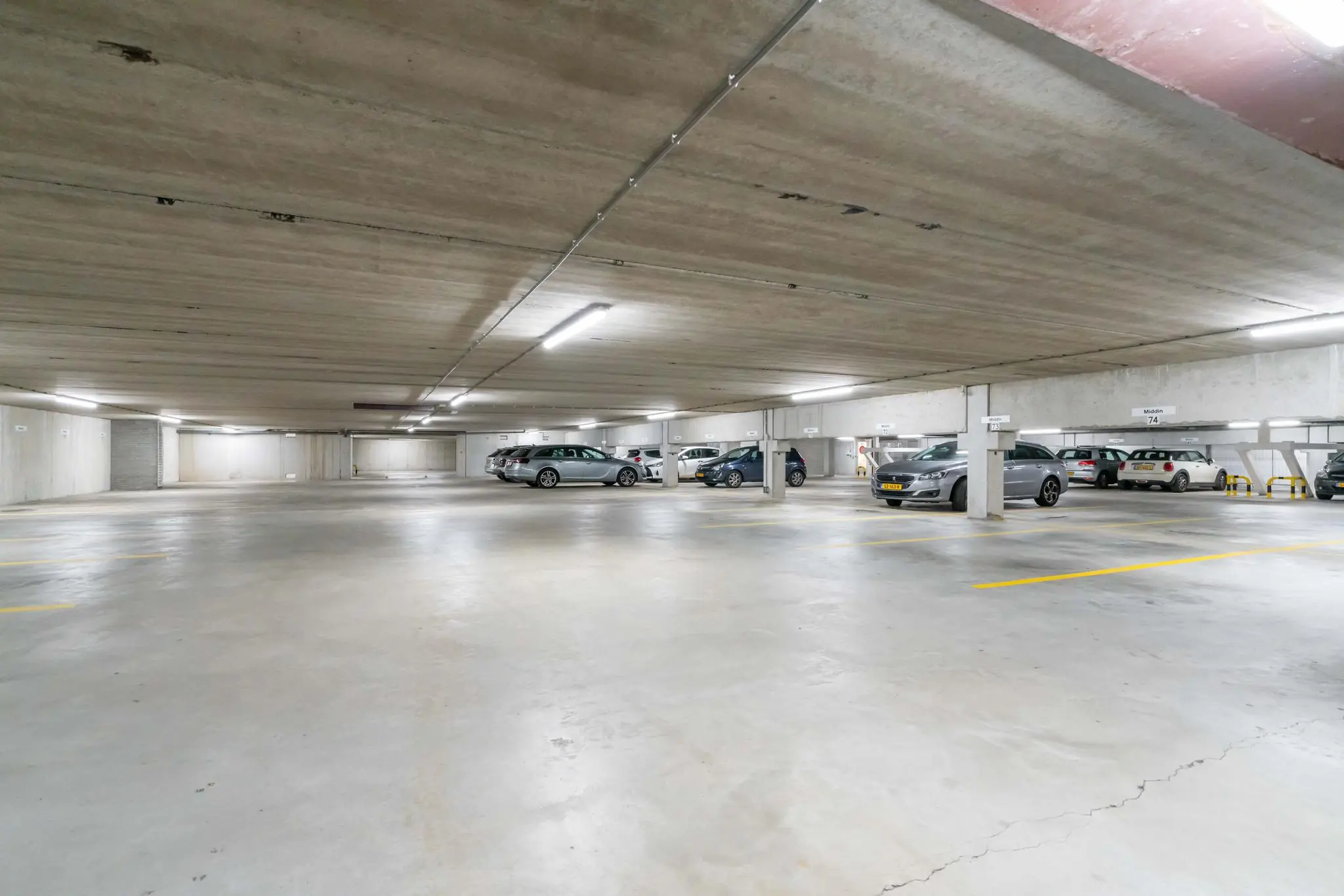 Ondergrondse parkeergarage aan de De Bruyn Kopsstraat met meerdere geparkeerde auto's en lege parkeerplekken.